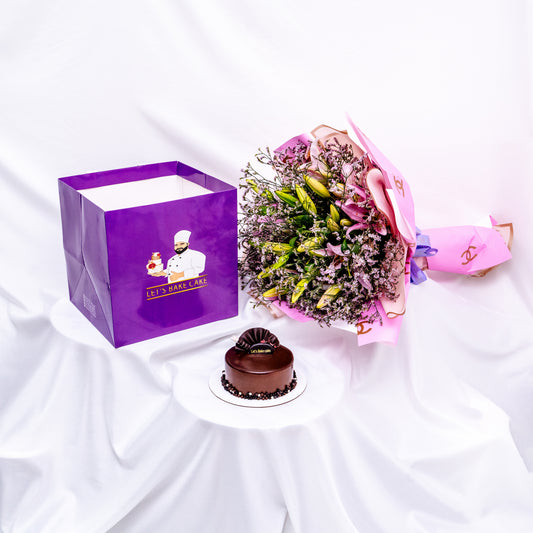 A luxury gift set featuring a rich chocolate bento cake, a large pink lily bouquet in designer wrap, and a signature 'Let's Bake Cake' purple gift bag on white silk, Abu Dhabi.