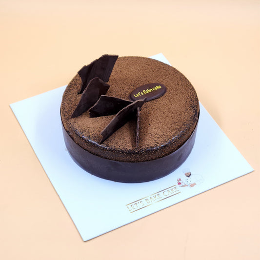A luxury dark chocolate mousse cake with cocoa dusting and handcrafted chocolate shards by Let's Bake Cake Abu Dhabi.