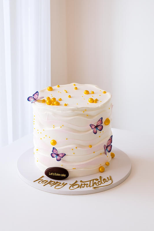 A luxury white and pink ombré wave-textured birthday cake with edible butterflies and golden pearls by Let's Bake Cake Abu Dhabi.