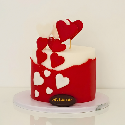 A modern red and white anniversary cake decorated with handcrafted heart toppers and a textured fondant wrap by Let's Bake Cake Abu Dhabi.