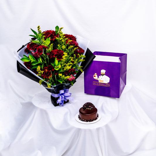 A premium gift set featuring a rich chocolate bento cake, a vibrant red and yellow flower bouquet in black wrap, and a signature 'Let's Bake Cake' purple gift bag on white silk, Abu Dhabi.