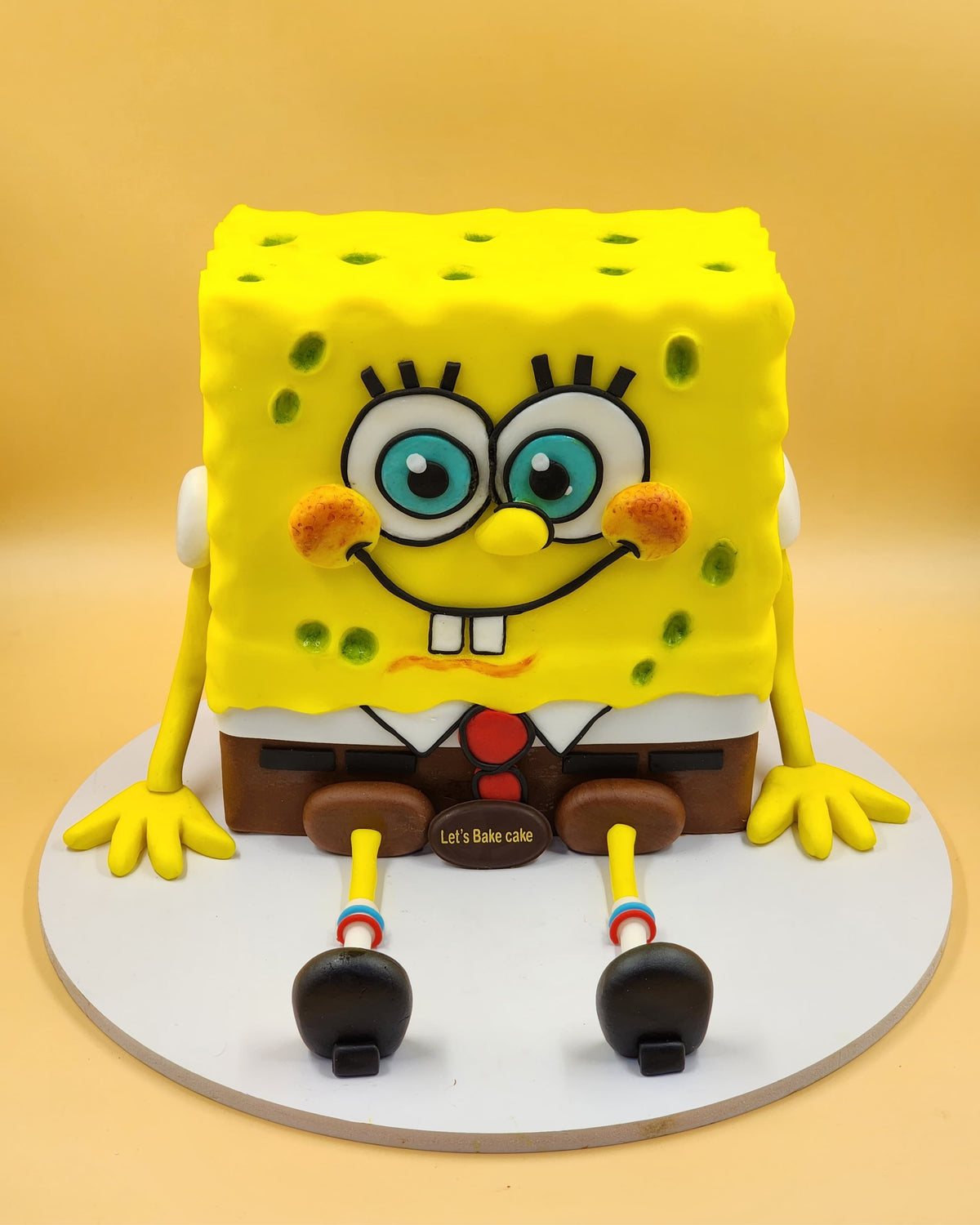 A 3D Spongebob Squarepants character birthday cake with hand-sculpted details and a yellow background by Let's Bake Cake Abu Dhabi.