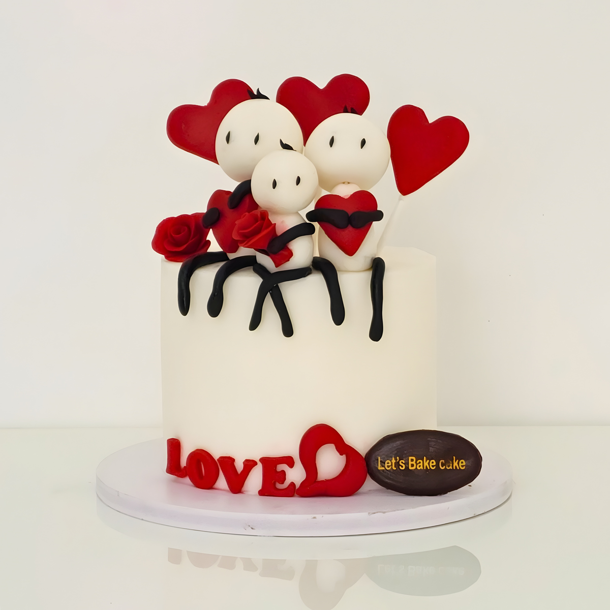 A custom white anniversary cake decorated with handcrafted fondant family figures, red hearts, and 'LOVE' lettering by Let's Bake Cake Abu Dhabi.