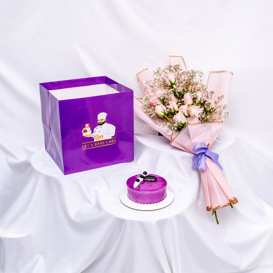An elegant gift combo featuring a soft pink rose bouquet with baby's breath, a signature purple glazed bento cake, and a luxury 'Let's Bake Cake' branded gift bag on a white silk background, Abu Dhabi