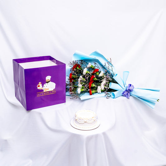 A premium gift set featuring a hand-piped white bento cake, a vibrant red and white flower bouquet in sky-blue wrap, and a signature 'Let's Bake Cake' purple gift bag on white silk, Abu Dhabi.