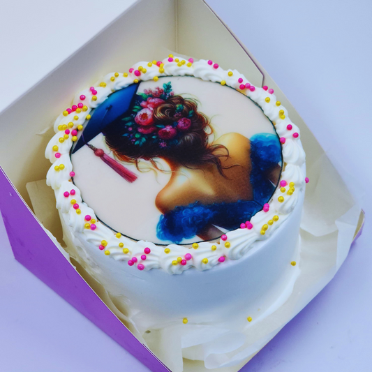 A luxury white graduation cake with a floral-themed edible image of a graduate girl and pink/gold sprinkles by Let's Bake Cake Abu Dhabi