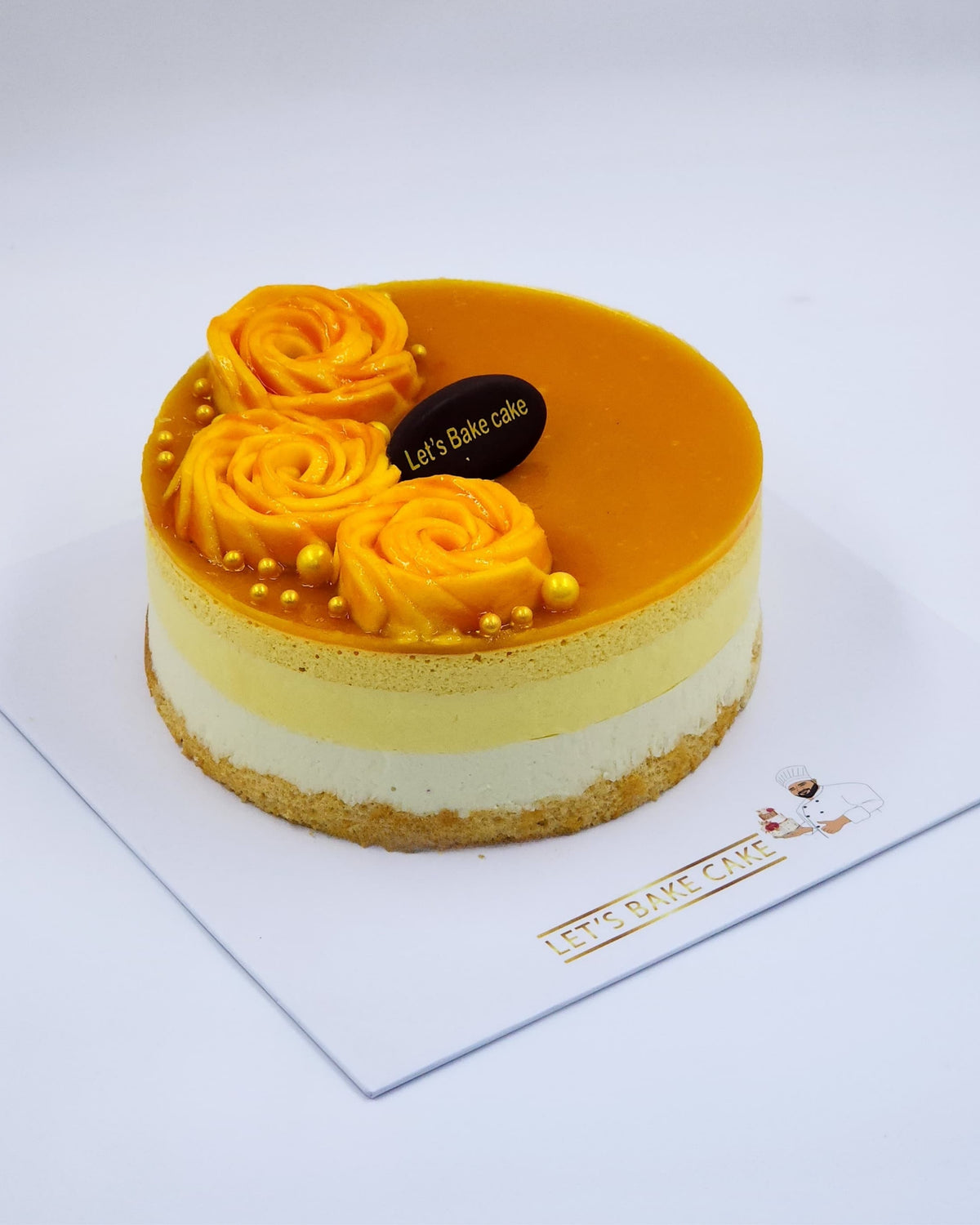 A luxury layered mango mousse cake decorated with fresh mango roses and gold edible pearls by Let's Bake Cake Abu Dhabi.
