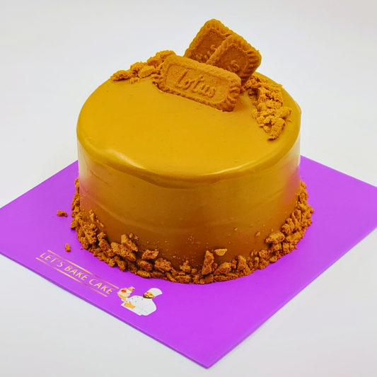 A luxury Lotus Biscoff cookie butter cake with a smooth caramel glaze and biscuit crumbles on a purple Let's Bake Cake board.