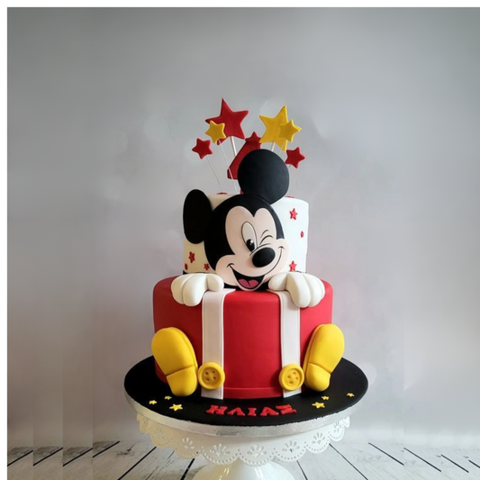 A luxury two-tier Mickey Mouse themed birthday cake with 3D boots, star toppers, and a winking Mickey face by Let's Bake Cake Abu Dhabi.