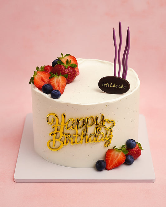 A luxury white minimalist birthday cake decorated with fresh strawberries, blueberries, and a gold 'Happy Birthday' topper by Let's Bake Cake Abu Dhabi.
