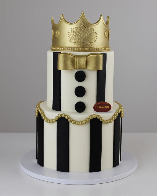 A luxury two-tiered black and white striped birthday cake topped with a majestic gold crown and gold pearl decorations by Let's Bake Cake Abu Dhabi.