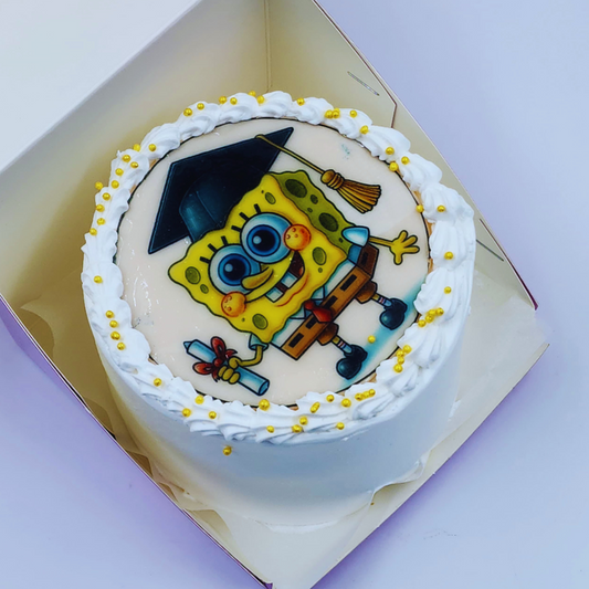 A luxury white graduation cake with a SpongeBob SquarePants edible image and golden sprinkles by Let's Bake Cake Abu Dhabi.