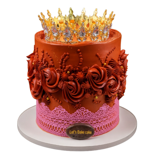 A luxury terracotta-red birthday cake featuring pink edible lace, piped rosettes, and a large crystal gold crown by Let's Bake Cake Abu Dhabi