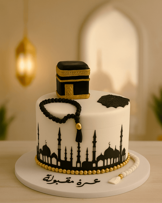 A luxury white Umrah Mubarak cake with a Kaaba topper, edible Tasbeeh, and Masjid silhouette by Let's Bake Cake Abu Dhabi