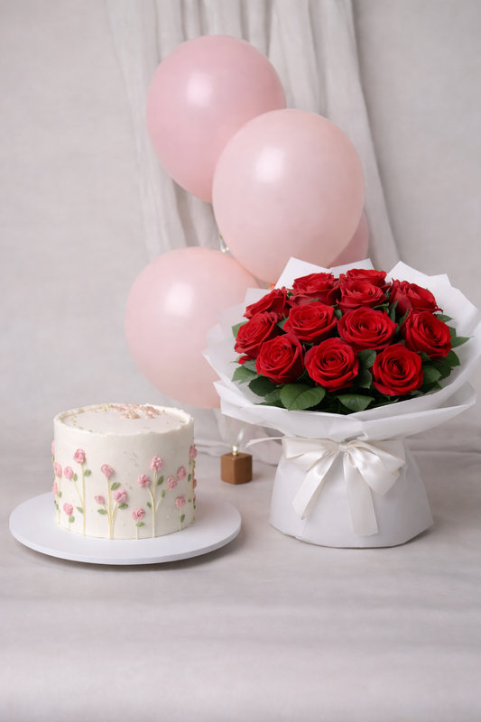 A luxury gift bundle featuring a small white cake with pink floral piping, a large bouquet of red roses, and pink balloons by Let's Bake Cake Abu Dhabi