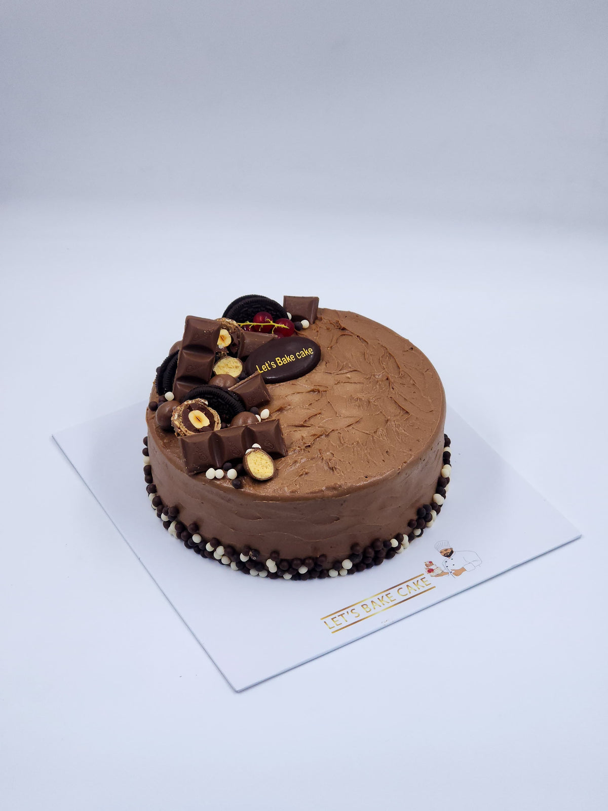 A luxury chocolate birthday cake loaded with Kinder bars, Oreos, and chocolate pearls by Let's Bake Cake Abu Dhabi.