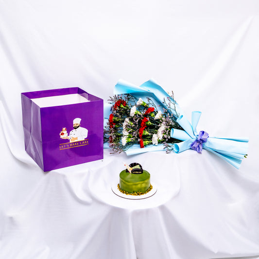 A premium gift set featuring a green pistachio glazed bento cake, a vibrant red and white flower bouquet in sky-blue wrap, and a signature 'Let's Bake Cake' purple gift bag on white silk, Abu Dhabi.