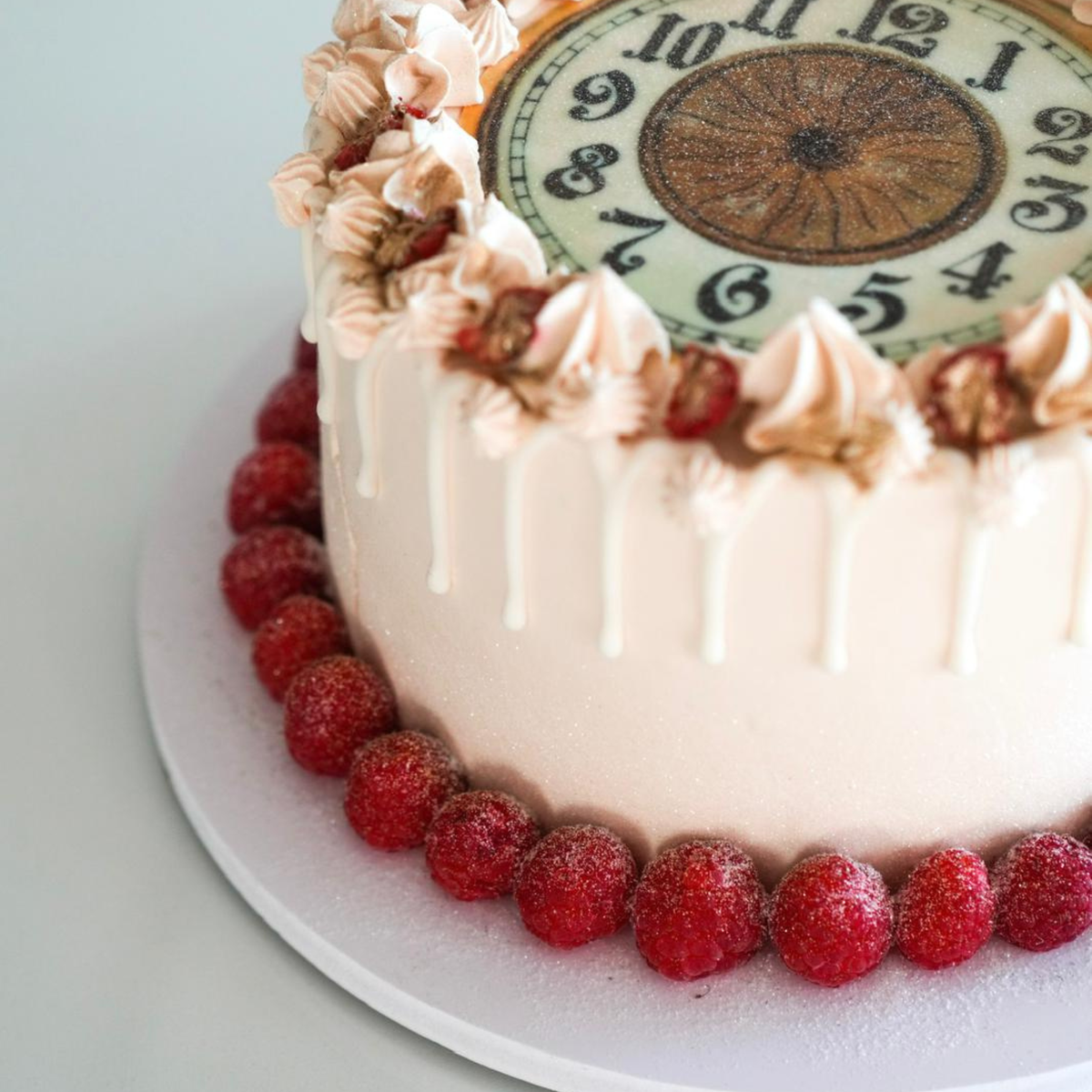 A macro close-up of a luxury cake showing silky white chocolate drip and a row of fresh raspberries by Let's Bake Cake Abu Dhabi.